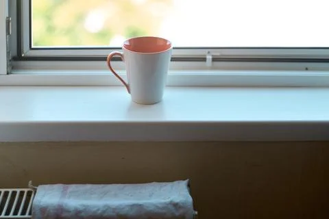 A ceramic coffee mug sitting on a windowsill in the morning light Stock Photos