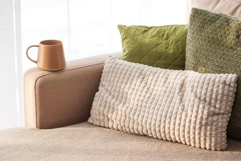 Ceramic Coffee Mug on Sofa Armrest with Textured Pillows. Cozy Home Interior Stock Photos