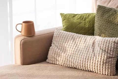 Ceramic Coffee Mug on Sofa Armrest with Textured Pillows. Cozy Home Interior Stock Photos