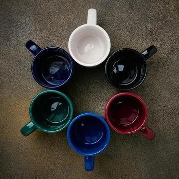 Ceramic colored mugs standing in a circle, close up, top view Stock Photos