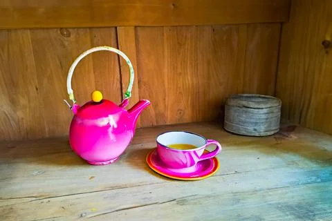 Ceramic cup and kettle of tea, coffe with a pink floral motif, wooden background Stock Photos