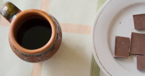 Ceramic cup of coffee and milk chocolate on plate. Top view, panorama. Concept 動画素材 240736392