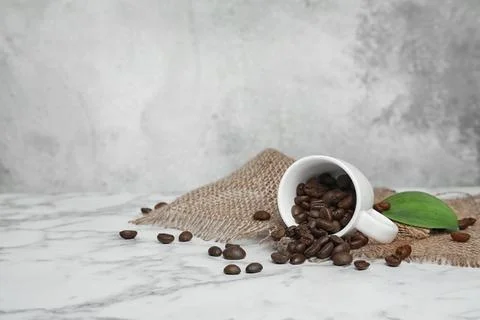 Ceramic cup with coffee beans on marble table 스톡 사진