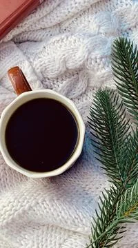 A ceramic cup filled with dark coffee rests on a soft knitted blanket. Fresh Foto stock