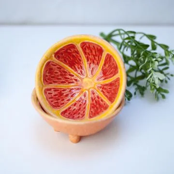 Ceramic cup in the form of half a grapefruit. Stock Photos
