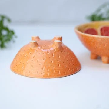 Ceramic cup in the form of half a grapefruit. Stock Photos