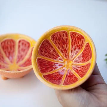 Ceramic cup in the form of half a grapefruit. Stock Photos