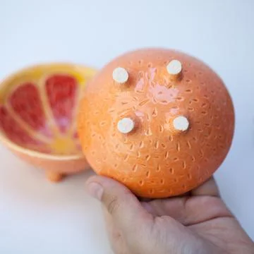 Ceramic cup in the form of half a grapefruit. Stock Photos
