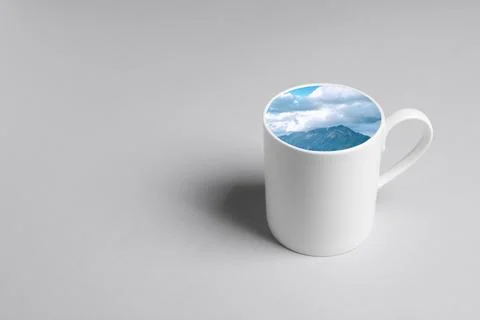 Ceramic cup with mountain landscape instead of drink on white background. S.. Stock Photos