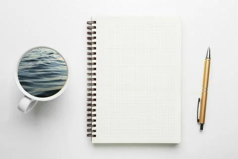 Ceramic cup with sea waves instead of drink, notebook and pen on white back.. Stock-Fotos
