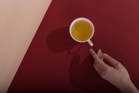 Ceramic cup with tea, on a red background. The harsh shade of the sun, the ar Stock Photos