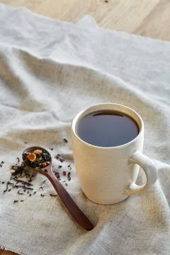 Ceramic cup of tea with scattered tea leaves on a napkin on rustic wooden Stock Photos