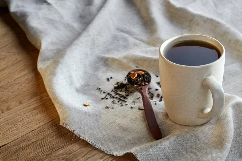 Ceramic cup of tea with scattered tea leaves on a napkin on rustic wooden Stock Photos