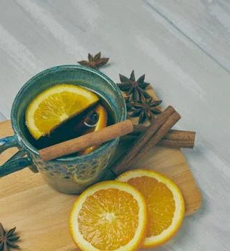 A ceramic cup of warming tea with cinnamon and orange on a rustic white table Stock Photos