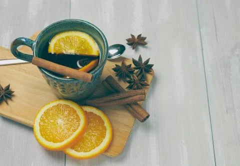 A ceramic cup of warming tea with cinnamon and orange on a rustic white table Stock Photos