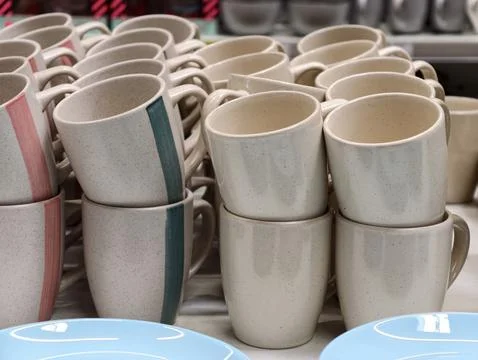 Ceramic cups and blue plates displayed on supermarket shelves forming a sim.. Fotos Stock