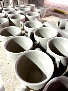 Ceramic cups crafted from clay are arranged on a surface, drying after bein.. Stock Photos
