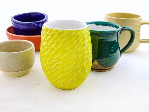 Ceramic cups of different colors and sizes close-up. Stock Photos