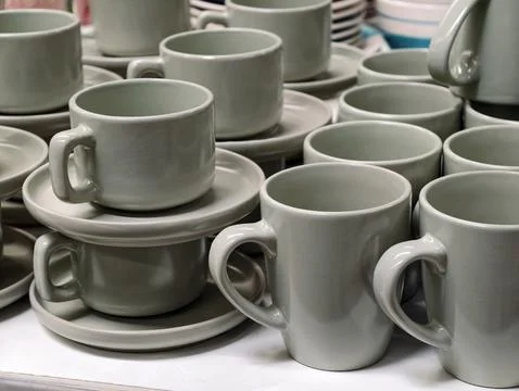 Ceramic cups in multiple shapes with saucers displayed in supermarket shelv.. Stock Photos