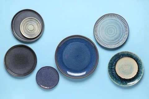 Ceramic dinnerware collection with blue and gray plates on a light blue backg Stock Photos