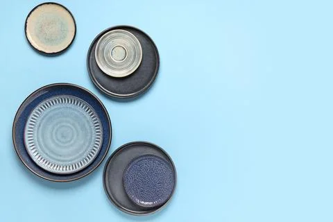 Ceramic dinnerware collection with blue and gray plates on light blue backgro Stock Photos