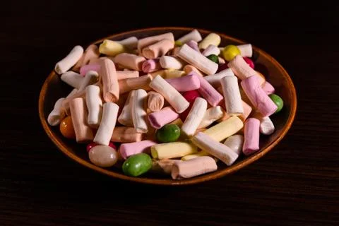 Ceramic dish with the different multi colored candies on a dark wooden table Stock Photos