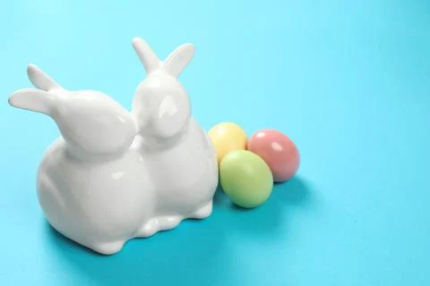 Ceramic Easter bunnies and dyed eggs on color background, space for text Stock Photos