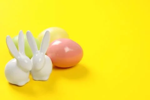 Ceramic Easter bunnies and dyed eggs on color background, space for text Stock Photos