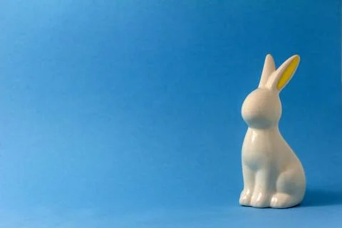 Ceramic Easter bunny on blue background, Easter minimalism concept using copy Stock Photos