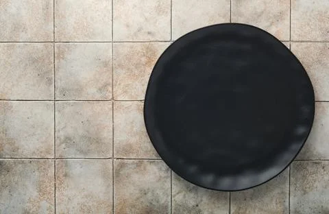 Ceramic empty black plate on old ceramic tile table background. Cooking stone Stock Photos