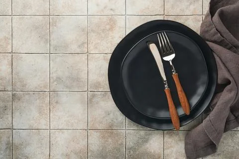 Ceramic empty black plate, silverware and linen kitchen towel napkin on old c Stock Photos