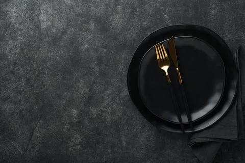Ceramic empty black plate, silverware and linen kitchen towel napkin on old b Stock Photos