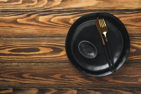 Ceramic empty black plate, silverware and linen kitchen towel napkin on old b Stock Photos