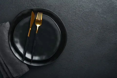 Ceramic empty black plate, silverware and linen kitchen towel napkin on old b Stock Photos