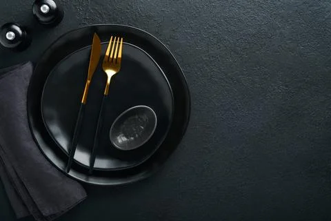 Ceramic empty black plate, silverware and linen kitchen towel napkin on old b Stock Photos