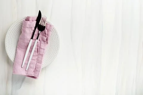 Ceramic empty white plate and pink linen kitchen towel napkin on old ceramic  Stock Photos