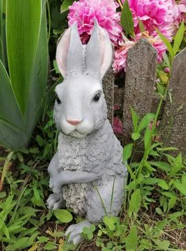 A ceramic figurine of a hare stands in a flower bed in the garden Stock Photos