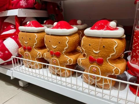 Ceramic gingerbread shaped jars with red hats and cheerful faces placed on .. Stock Photos