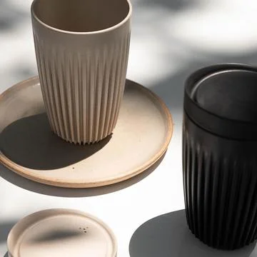 Ceramic glasses with vertical lines type striations with their ceramic plate whi Stock Photos