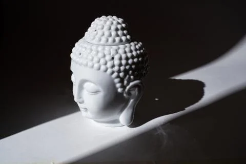 Ceramic head of Buddha statue in the ray of light. Stock Photos