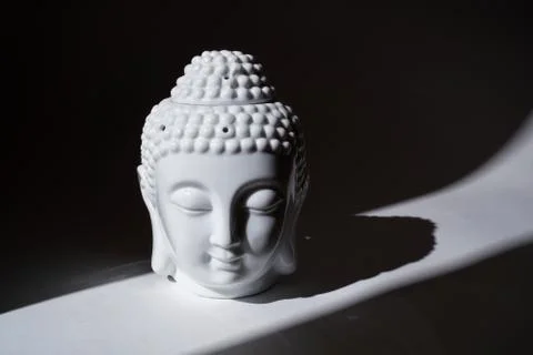 Ceramic head of Buddha statue in the ray of light. Stock Photos