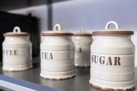 Ceramic jars labeled coffee, tea, sugar arranged on shelf, vintage kitchen de Stock Photos