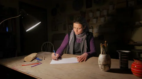 Ceramic maker designing artwork with pencil in her atelier slide-cam wide shot Stock Footage 61950449