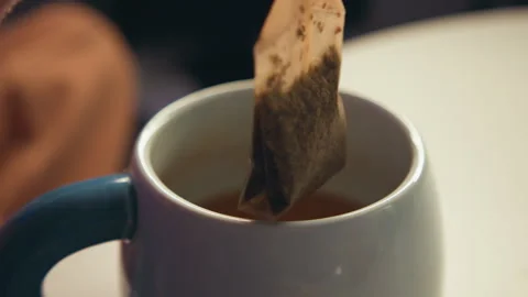 Ceramic mug with brewed tea, teabag lifted away, faint steam rising and gentle Stock Footage 347618290