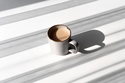 Ceramic Mug of Coffee or Tea Casting a Strong Shadow on a White Surface Stock Photos