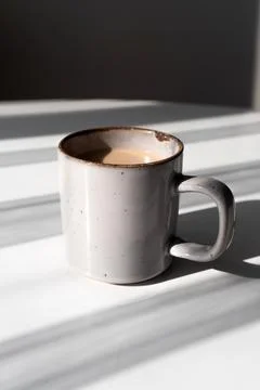 Ceramic Mug of Coffee or Tea Casting a Strong Shadow on a White Surface Stock Photos