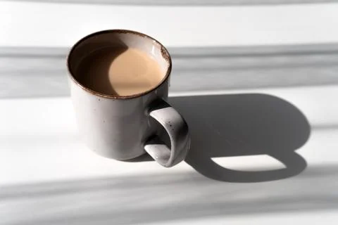 Ceramic Mug of Coffee or Tea Casting a Strong Shadow on a White Surface Stock Photos