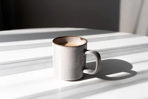 Ceramic Mug of Coffee or Tea Casting a Strong Shadow on a White Surface Foto stock