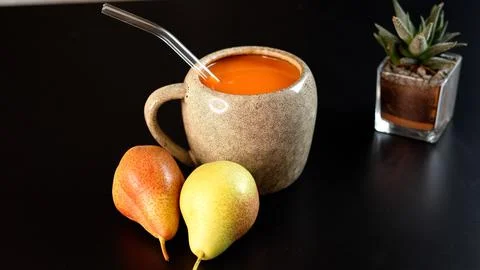 Ceramic mug filled with vegetable beverage, pears beside, succulent plant on Stock Photos