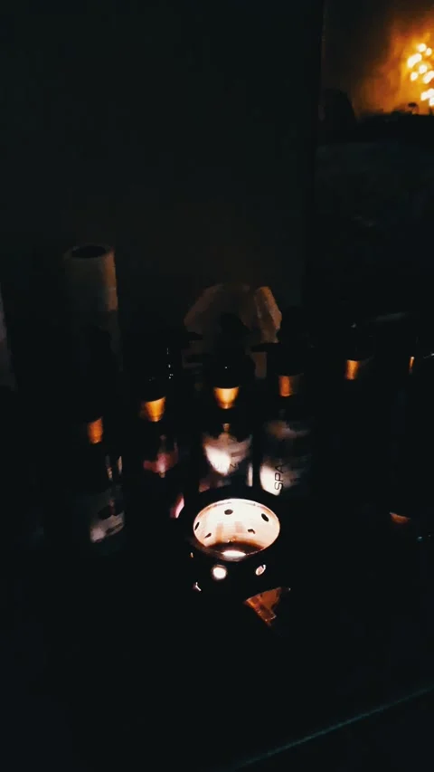 Ceramic Oil Burner Glowing Between Small Bottles in Dark Room Stock Footage 321972745
